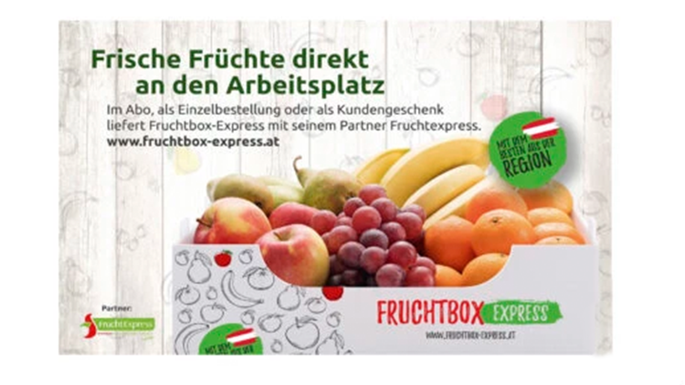 Korb voller frischer Früchte in einer weißen Box mit der Werbung 'Fruchtbox Express' – Lieferung frischer Früchte an den Arbeitsplatz